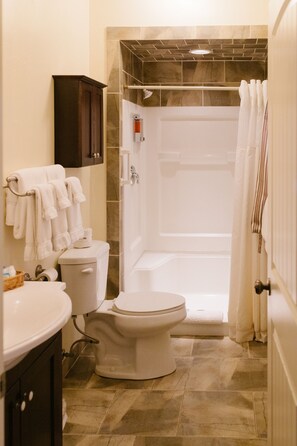 A bathroom with a toilet, sink, and shower area.