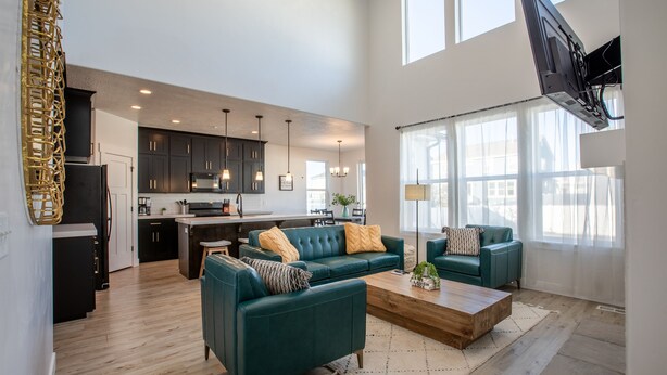 A spacious living area with two teal sofas, a wooden coffee table, and a kitchen in the background. - Family Gathering Place 6 BD Home Hot Tub sleeps 12 (American Fork)