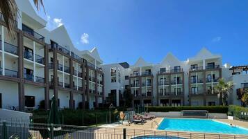 Un hôtel doté de nombreux balcons, d’une piscine et surplombant un ciel d’un bleu limpide.