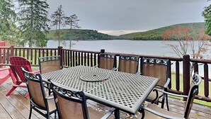 A deck with a table and chairs overlooking a lake, surrounded by trees and hills. - Bear Hollow Lodge by Taylor Made Deep Creek (Oakland)