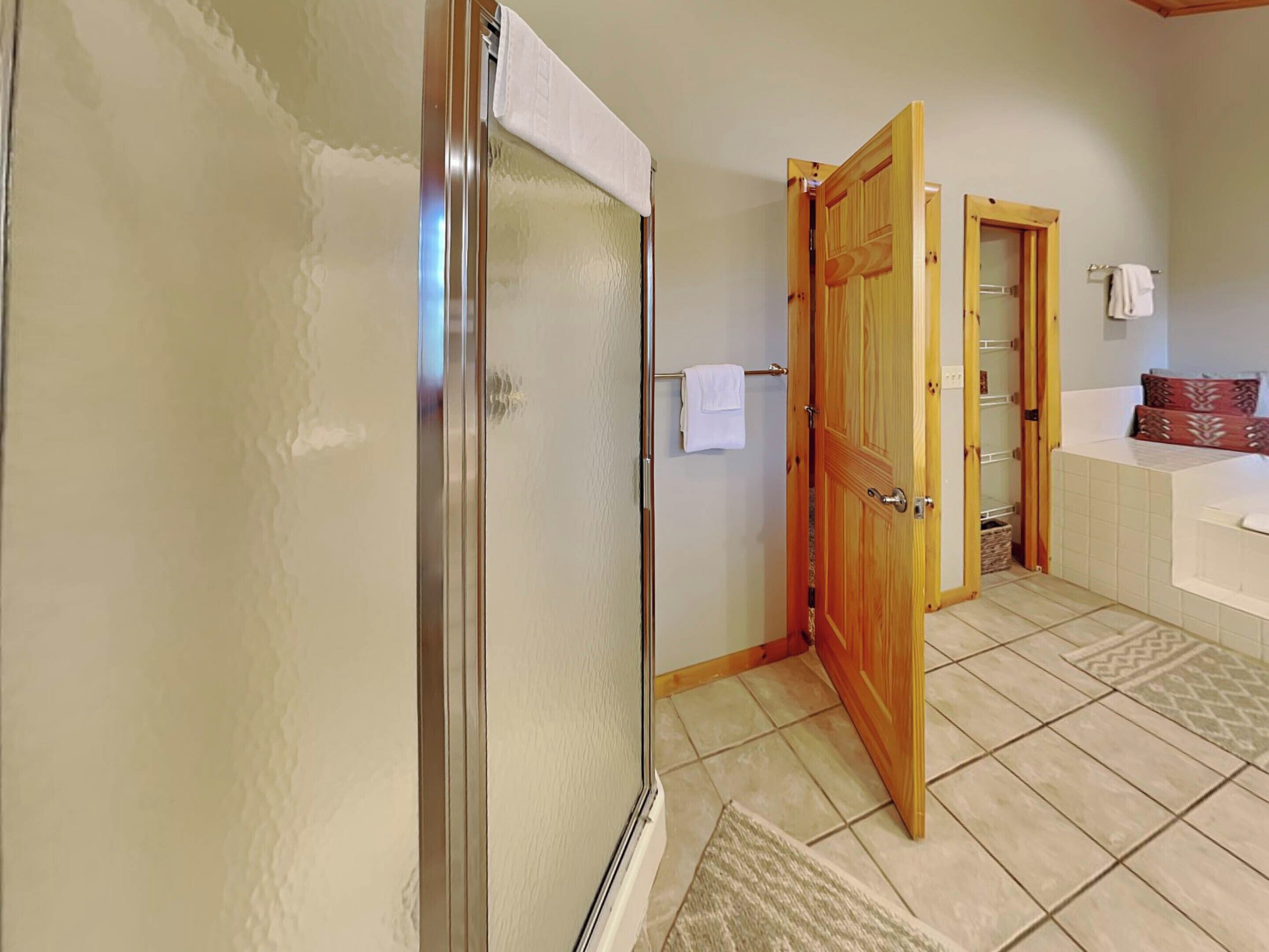 Une salle de bain avec une douche, une porte en bois, un porte-serviettes et une baignoire.