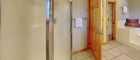 Une salle de bain avec une douche, une porte en bois, un porte-serviettes et une baignoire.