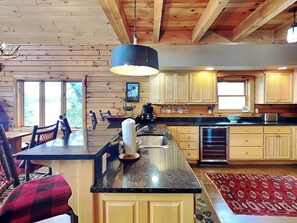 A spacious kitchen with wooden cabinets, a granite countertop, and a large island with a sink. - Bear Hollow Lodge by Taylor Made Deep Creek (Oakland)