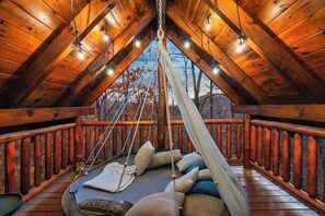 A wooden deck with a hammock and pillows, a wooden railing, and a view of trees. - Private LOG Cabin - Fall Views - Hot Tub - Arcade & Pool Table -  9 MI to Pkwy (Sevierville)