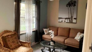 Un salon avec un canapé marron, une table basse en verre et un fauteuil décoratif.