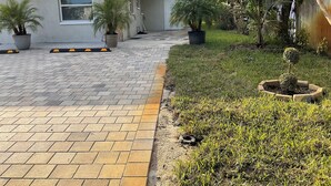 Il s’agit d’une propriété résidentielle dotée d’une allée pavée, de plantes en pot et d’une pelouse.