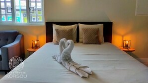 A hotel room with a bed, two bedside lamps, a chair, and a window with a view. - Studio (Willemstad)