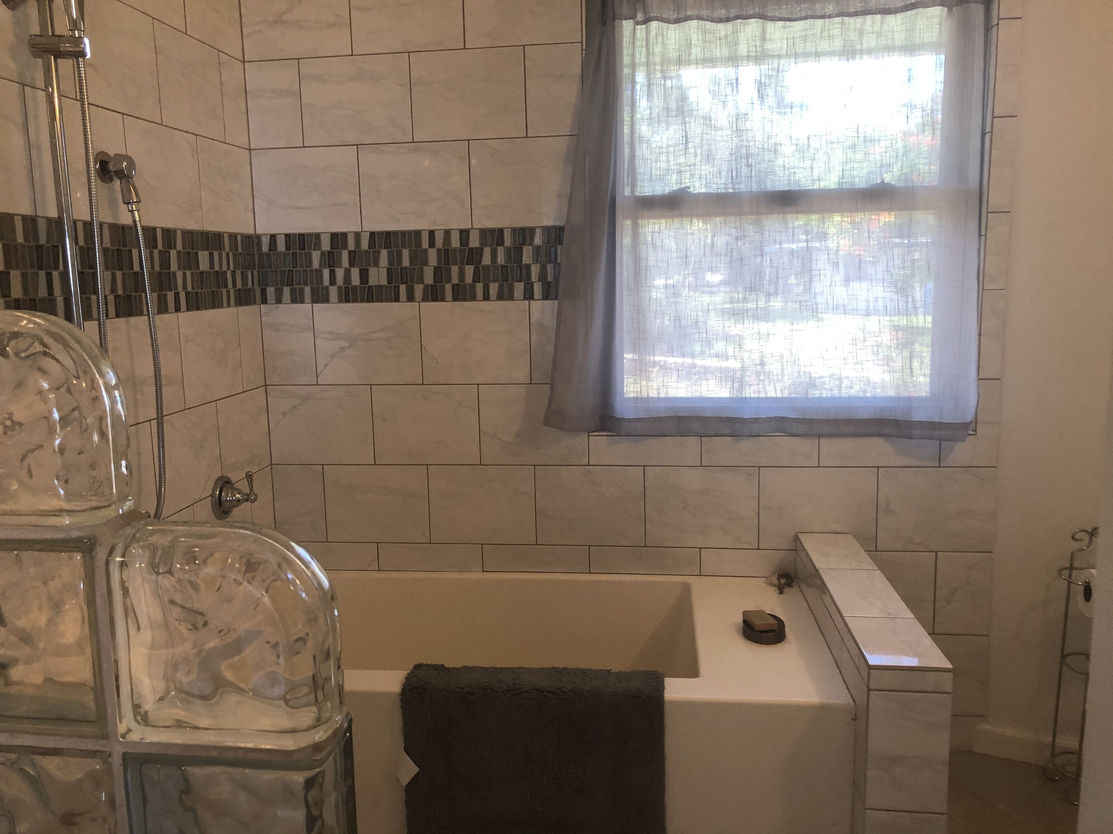 A bathroom with a bathtub, a shower, and a window with a view.