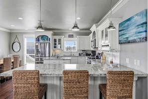 A spacious kitchen with a large island, white cabinetry, and a view to the outside.