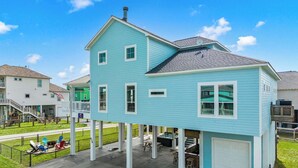 Une maison à deux étages avec un garage, une terrasse couverte et un petit espace extérieur aménagé pour s’asseoir.