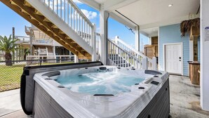 Un bain à remous situé dans un espace extérieur abrité, avec un escalier en bois menant à un deuxième niveau.