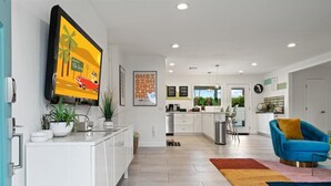 Una cocina moderna con armarios blancos, un televisor de pantalla plana grande y una alfombra colorida.