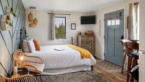 Un dormitorio con cama, mesitas de noche, televisor y ventana.