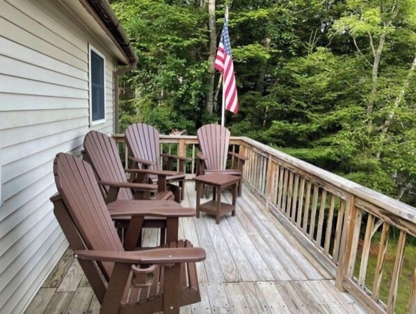 Relax on the deck surrounded by lush greenery, perfect for social gatherings or unwinding in the fresh air.