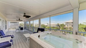 A covered outdoor deck with a hot tub, seating area, and ceiling fans. - 360* Views at "LGI Paradise" ~ Screened Porch w/ Hot Tub, Golf Cart included (Placida)