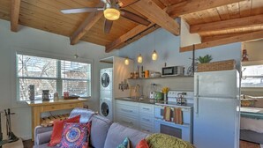 A compact living space with a sofa, kitchen area, and a ceiling fan.