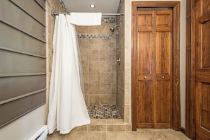 Un área de ducha con cortina, paredes de azulejos y una puerta de madera.