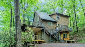 A two-story cabin with a balcony and a staircase leading to the upper level. - Bearadise Found by Taylor Made Deep Creek (Swanton)