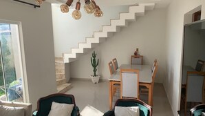 Ein modernes Wohnzimmer mit Treppe, Essbereich und großem Fenster.