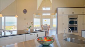 A modern kitchen with a large island, stainless steel appliances, and a view of the beach. - 45 Steps - The Culinary Beachside Inn (Goose River)