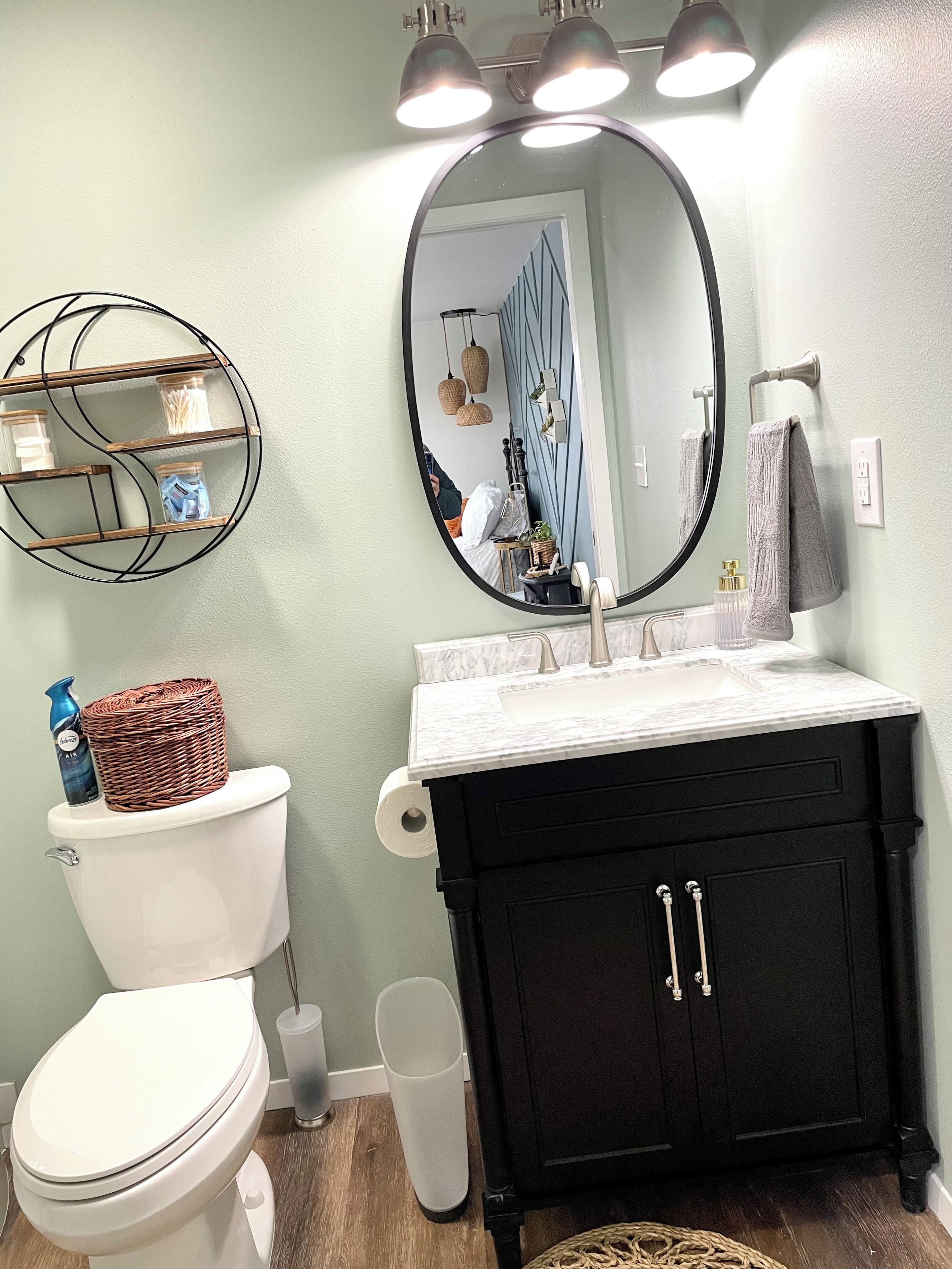 Een badkamer met een wit toilet, een zwart wastafelmeubel en een spiegel.