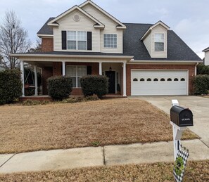 Stunning two-story home with a central entrance, covered porch, and garage.