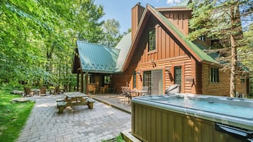 A log cabin with a patio area, outdoor seating, and a hot tub.
