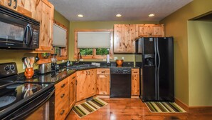 A kitchen with wooden cabinets, a black refrigerator, a microwave, a stove, and a dishwasher.