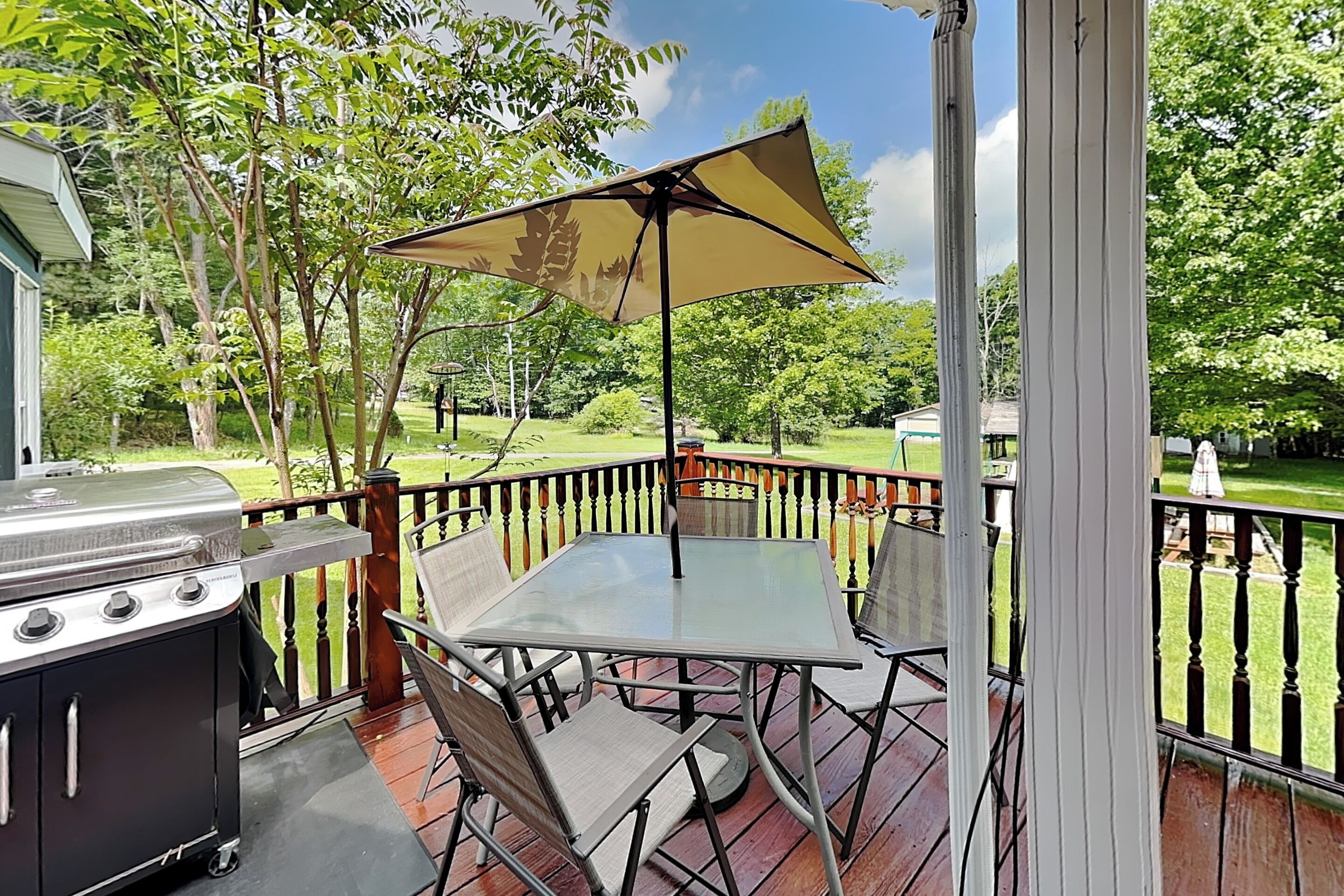 A covered outdoor patio with a grill, a table, and chairs.