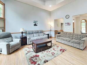 A spacious living room with a grey sofa, a patterned sofa, a wooden coffee table, and a floral rug. - Beautiful Adventure by Taylor Made Deep Creek (Swanton)