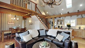 A spacious living room with a leather sectional sofa, a round coffee table, and a staircase leading to an upper level. - Bearfoot Lodge by Taylor Made Deep Creek (Oakland)