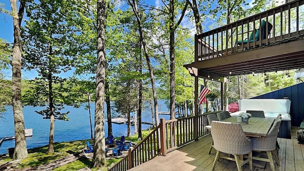 A deck with outdoor seating, a view of a lake, and a flag. - Bearfoot Lodge by Taylor Made Deep Creek (Oakland)
