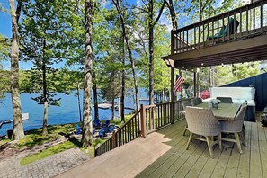 A deck with outdoor seating, a view of a lake, and a flag. - Bearfoot Lodge by Taylor Made Deep Creek (Oakland)