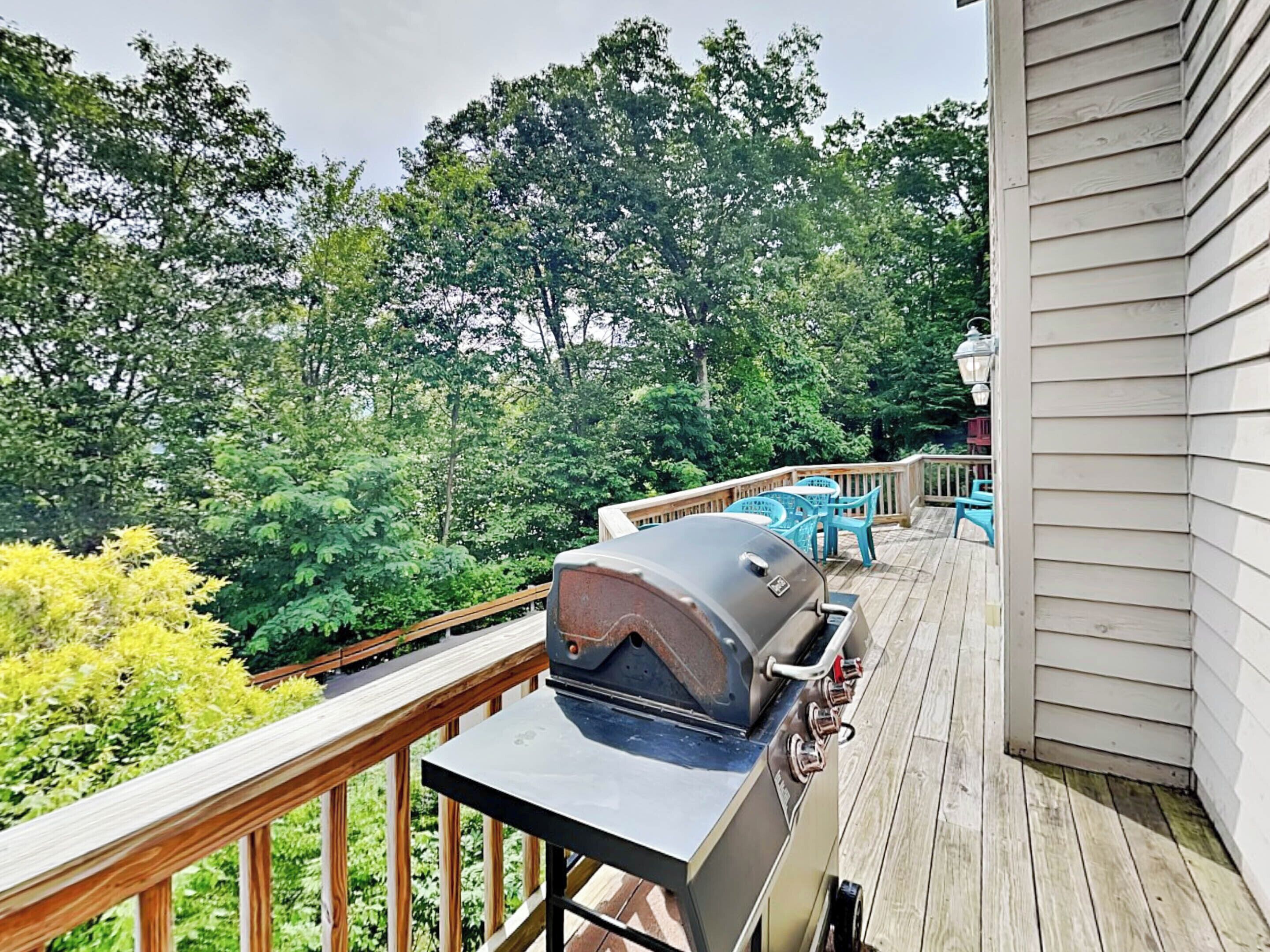 Eine Terrasse mit Grill, Gartenmöbeln und Blick auf ein Waldgebiet.