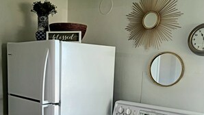 Una cocina con un refrigerador y estufa blancos, un reloj de pared y un espejo decorativo.