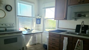 Una cocina con armarios de madera, una estufa blanca, un fregadero y una ventana con persianas.