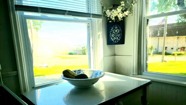 Una cocina con un bol en la encimera, una ventana con persianas y un adorno en la pared.