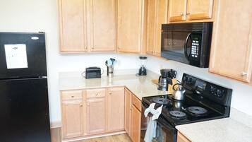 A kitchen with wooden cabinets, a black refrigerator, a microwave, a stove, and a toaster.