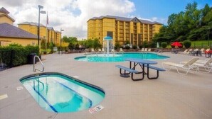 Ein Hotelpoolbereich mit mehreren Pools, Liegestühlen und einem Picknicktisch.