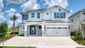 A two-story house with a stone facade, a garage, and a well-maintained lawn. - The Themepark Palace with Home Theater at Encore (Kissimmee)