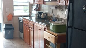 Eine Küche mit Holzausbau, einem schwarzen Kühlschrank, einem Herd und einem Fenster mit Jalousien.