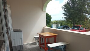 A balcony with a radiator, a small table, and a blue crate. - AIR Residence relax in your home away from home centrally located on Anguilla (The Valley, Anguilla)