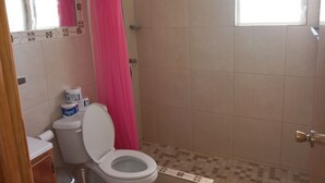 Ein Badezimmer mit Toilette, Dusche und einem Fenster.