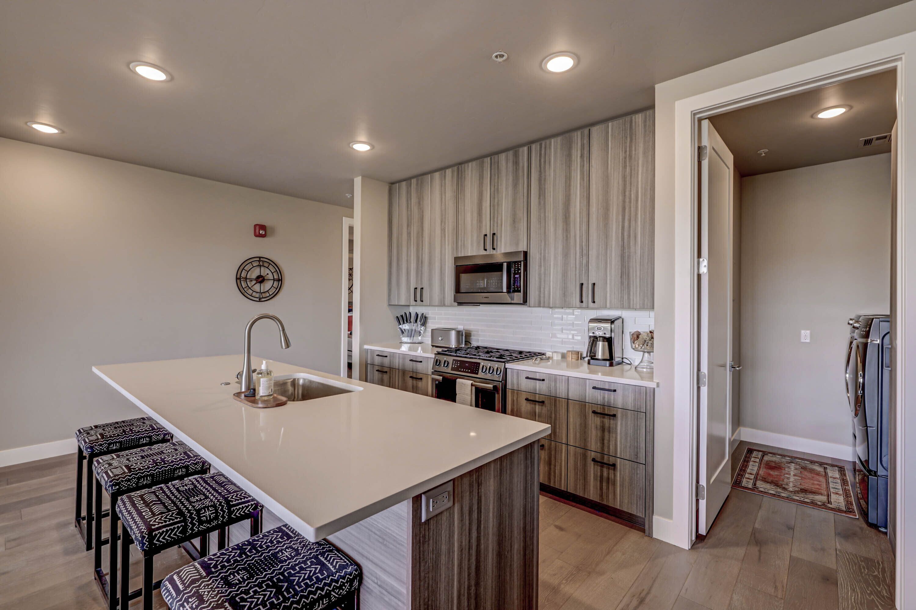 A modern kitchen with a central island, built-in appliances, and a seating area with stools.