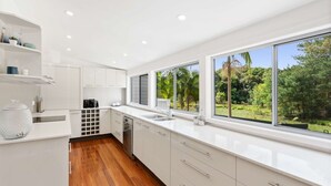 Una cocina moderna con armarios blancos, lavavajillas y un ventanal con vistas a zonas verdes.