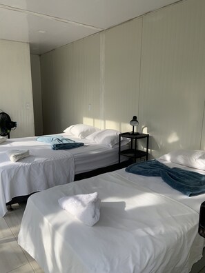 Two single beds with white linens and a table lamp on a nightstand.