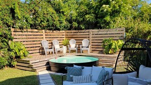 A patio with a round table, two sofas, and a small pool.