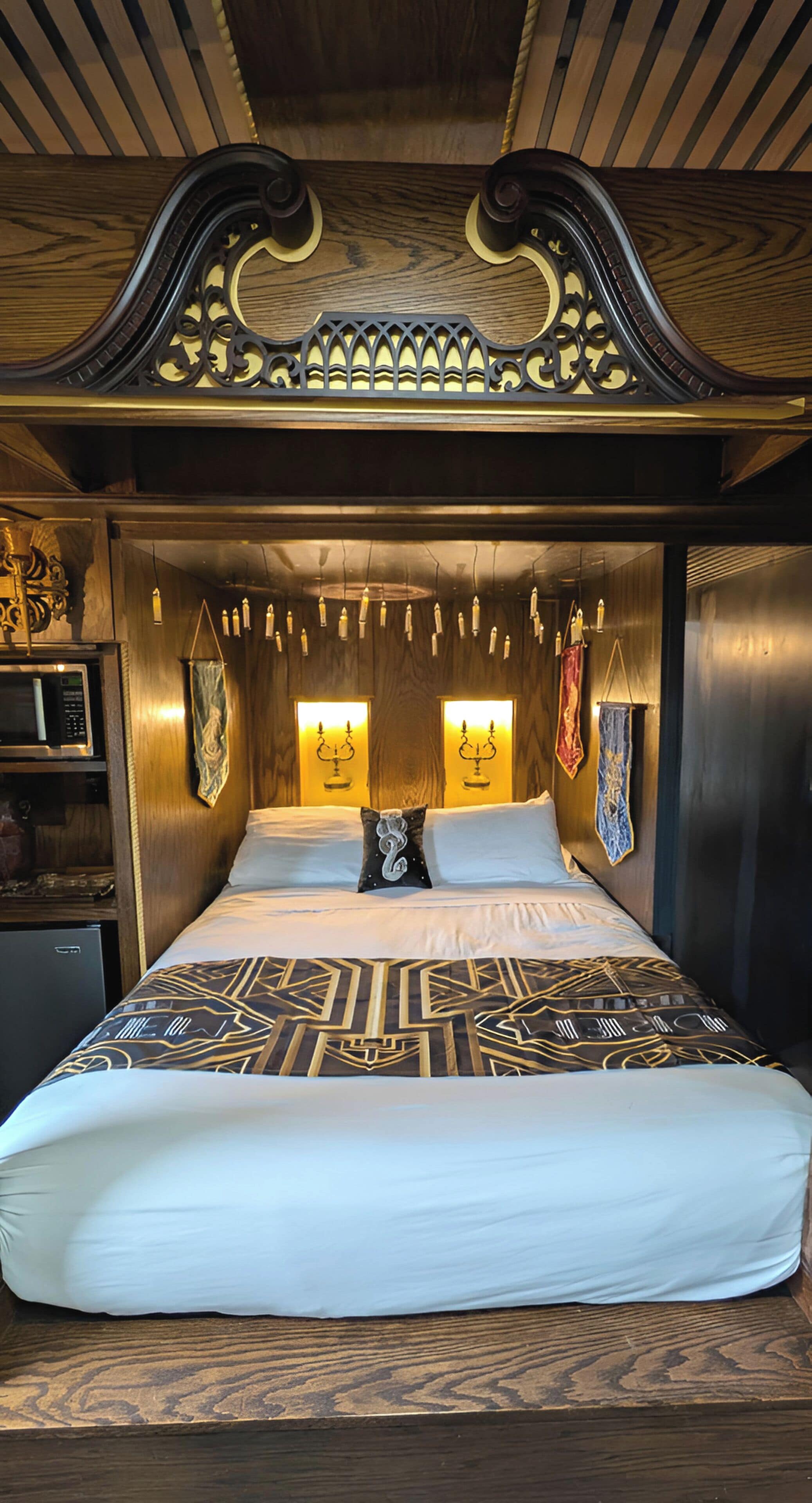 A bed with a patterned bedspread, a headboard with intricate designs, and wall-mounted lights.