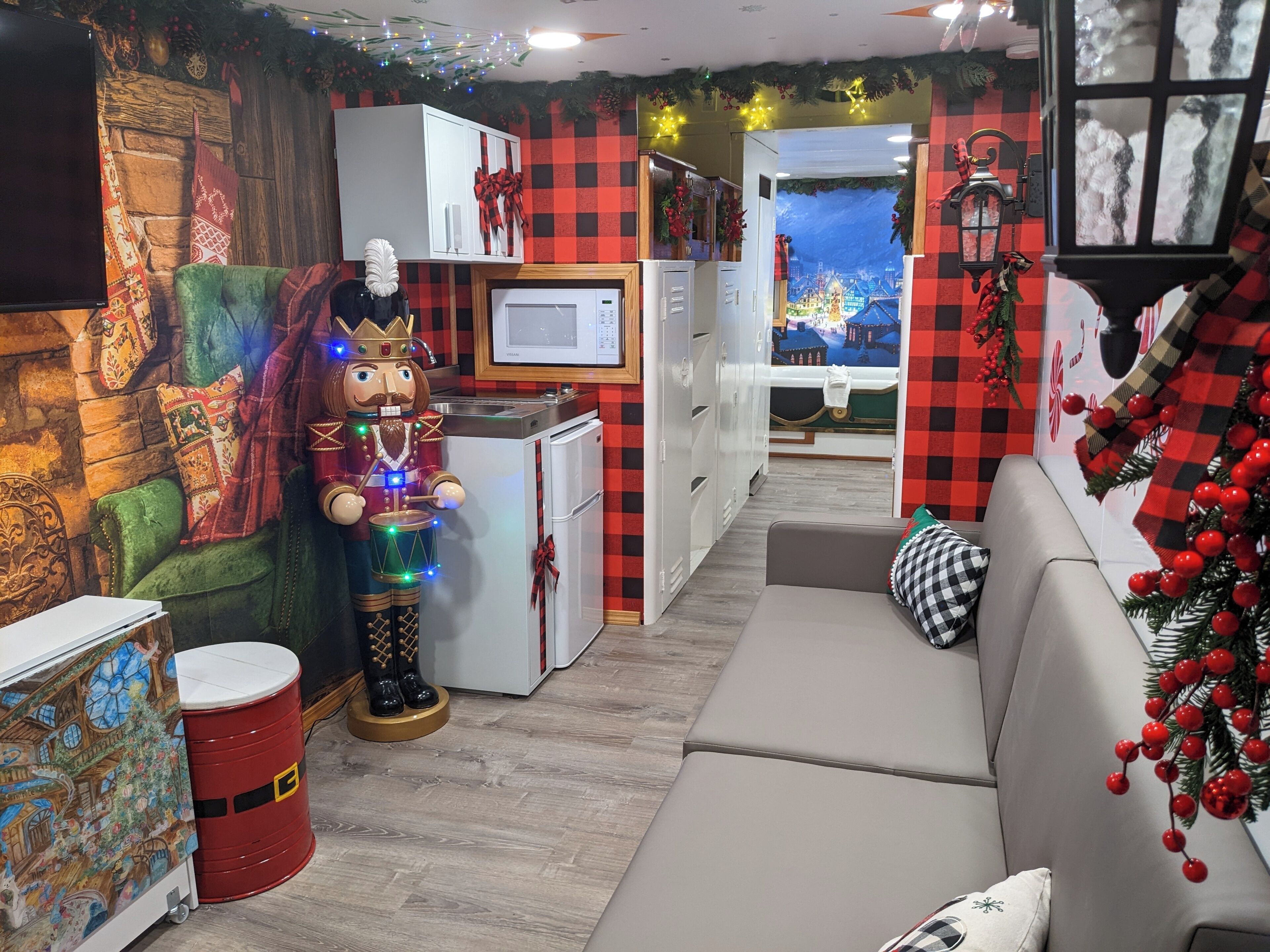 Une pièce chaleureuse avec une grande figurine de casse-noisette, un réfrigérateur blanc, un canapé et une fresque murale.