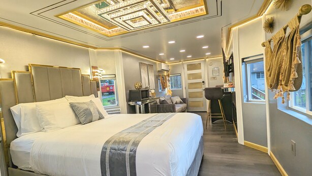 A modern hotel room with a large bed, a sofa, a desk, and a view of the outside. - Olympic Railway Inn (Sequim)
